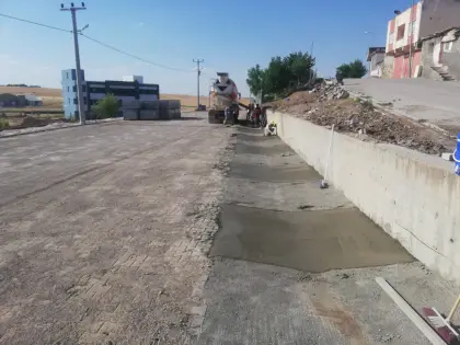 Diyarbakır altyapı projesinde yol kenarı yağmur suyu drenajı için kurulan kalıplara transmikserden beton dökümü yapılması ve betonun vibratörle sıkıştırılması