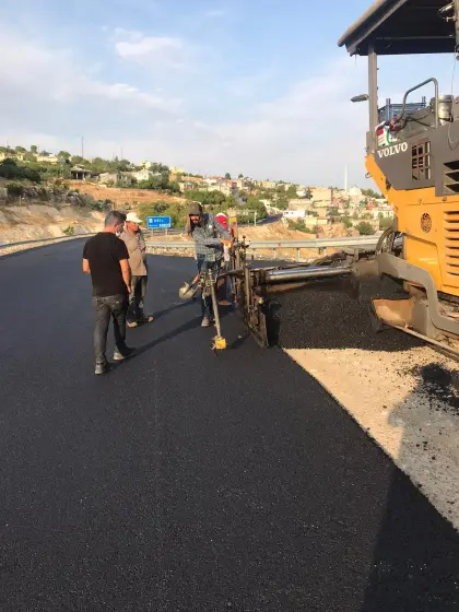 Diyarbakır Eğil'de uzman asfalt firması kontrolünde finişer iş makinası ile yola sıcak asfalt dökümü ve serimi yapılan an