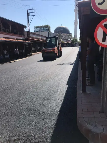 Diyarbakır Eğil ilçesinde yeni dökülen sıcak asfalt malzemesini ağır sanayi silindiri ile sıkıştırarak pürüzsüzleştiren yol yapım çalışması