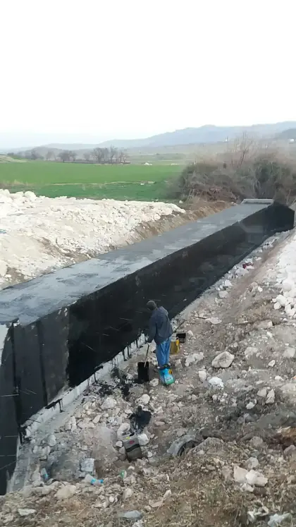 Diyarbakır Dicle yol projesinde betonarme menfez yapısının toprak altında kalacak yüzeylerine su yalıtımı sağlamak amacıyla uygulanan siyah bitüm astar çalışması