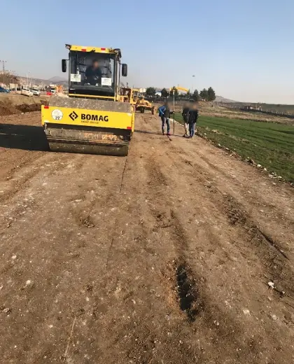 Diyarbakır yol şantiyesinde harita mühendislik ekibi kontrolünde stabilize malzeme serimi sonrası silindir iş makinesi ile zemin sıkıştırma işlemi
