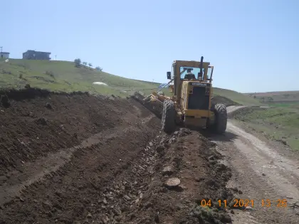 Diyarbakır altyapı müteahhiti kontrolünde stabilize yolun kenar eğimlerini ayarlamak için greyder şevlendirme çalışması yapıyor